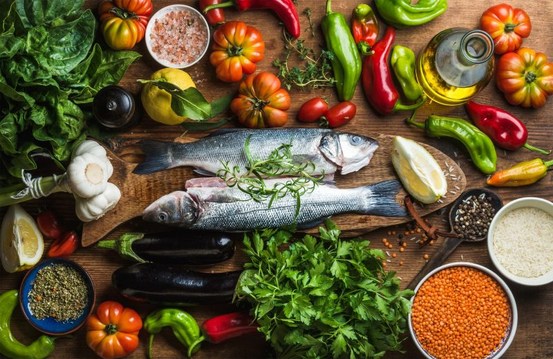 Een selectie van de beste voeding om af te vallen met verse groenten, fruit, magere eiwitten en gezonde vetten op een houten tafel